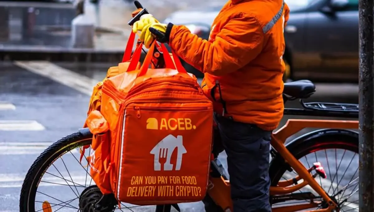 Food delivery courier with ACEB branded bag illustrating crypto payments for food delivery services.
